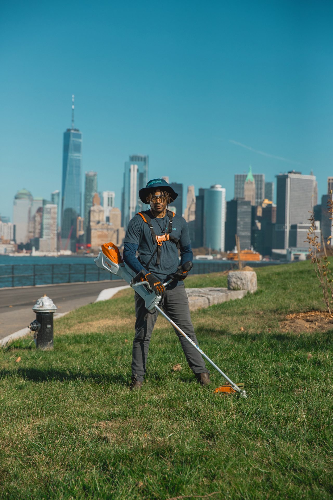 Mitarbeiter von Governors Island mit Arbeitshandschuhen stehen auf dem Rasen und halten eine Akku-Motorsense FSA 200 in der Hand