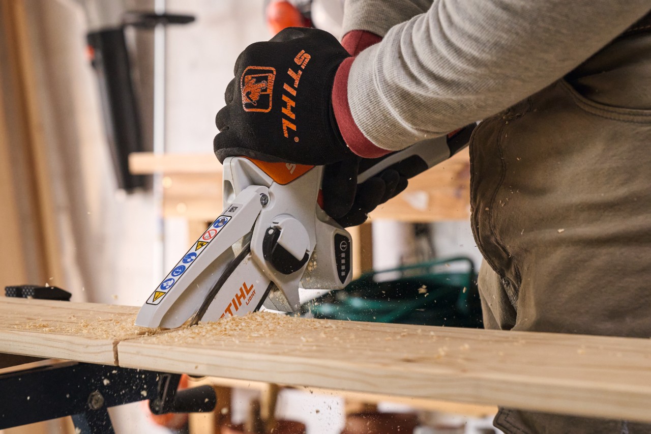 Ein Mann sägt Holzbretter mit einem Akku-Gehölzschneider STIHL GTA 26 zurecht