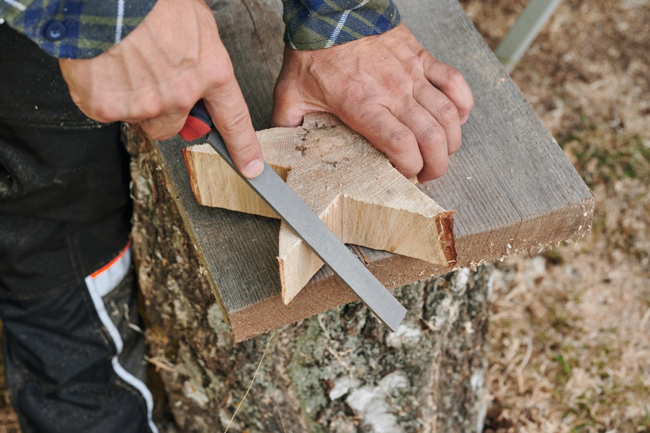 Eine Person bearbeitet einen selbstgemachten Holzstern mit einer Feile