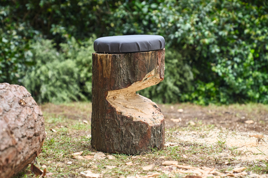 Selbstgebauter Holzstuhl vor einem Brennholzstapel 