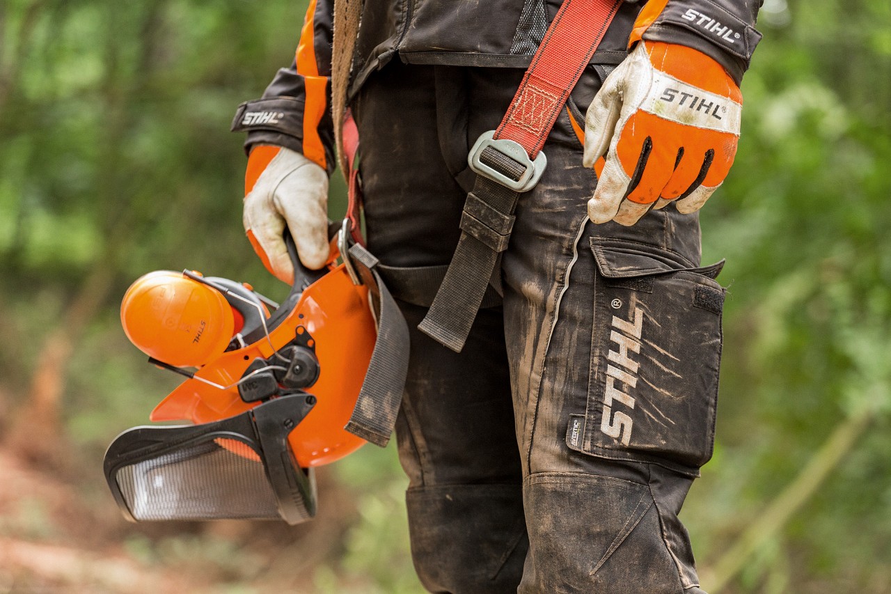 Personne en pantalon et gants de travail STIHL tenant un casque