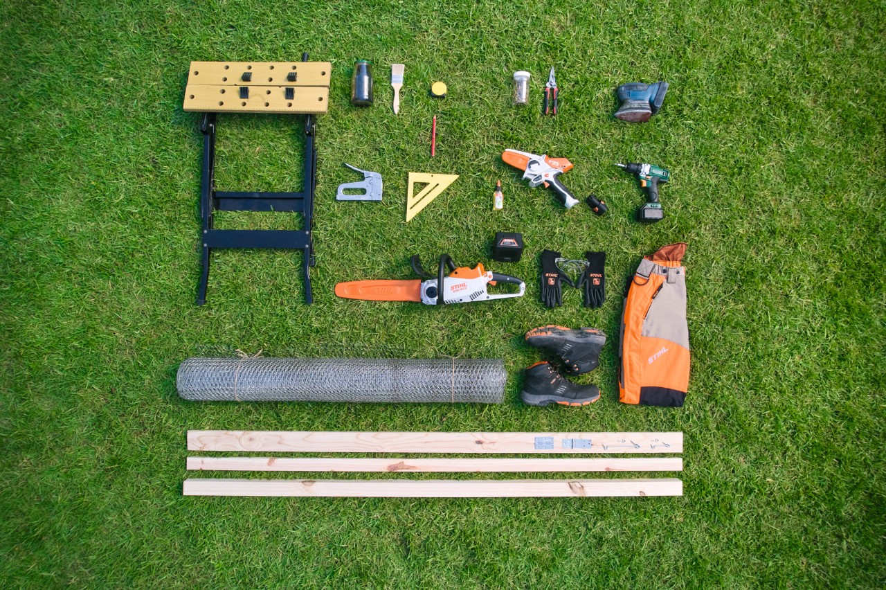 Vue aérienne des matériaux et outils nécessaires pour construire soi-même un bac à compost, disposés les uns à côté des autres sur une pelouse