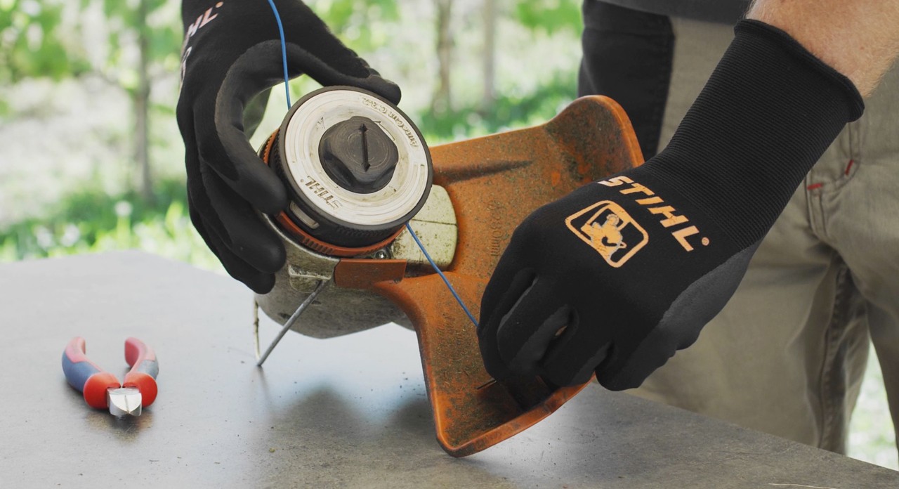 Une personne enroule le fil de débroussailleuse à batterie STIHL FSA 57 