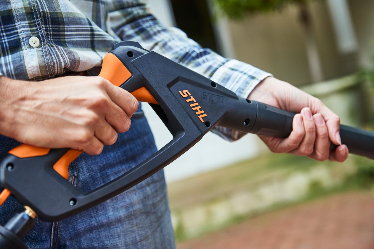 Une personne actionnant le pistolet du nettoyeur haute pression STIHL RE 130 PLUS éteint en vue de son utilisation