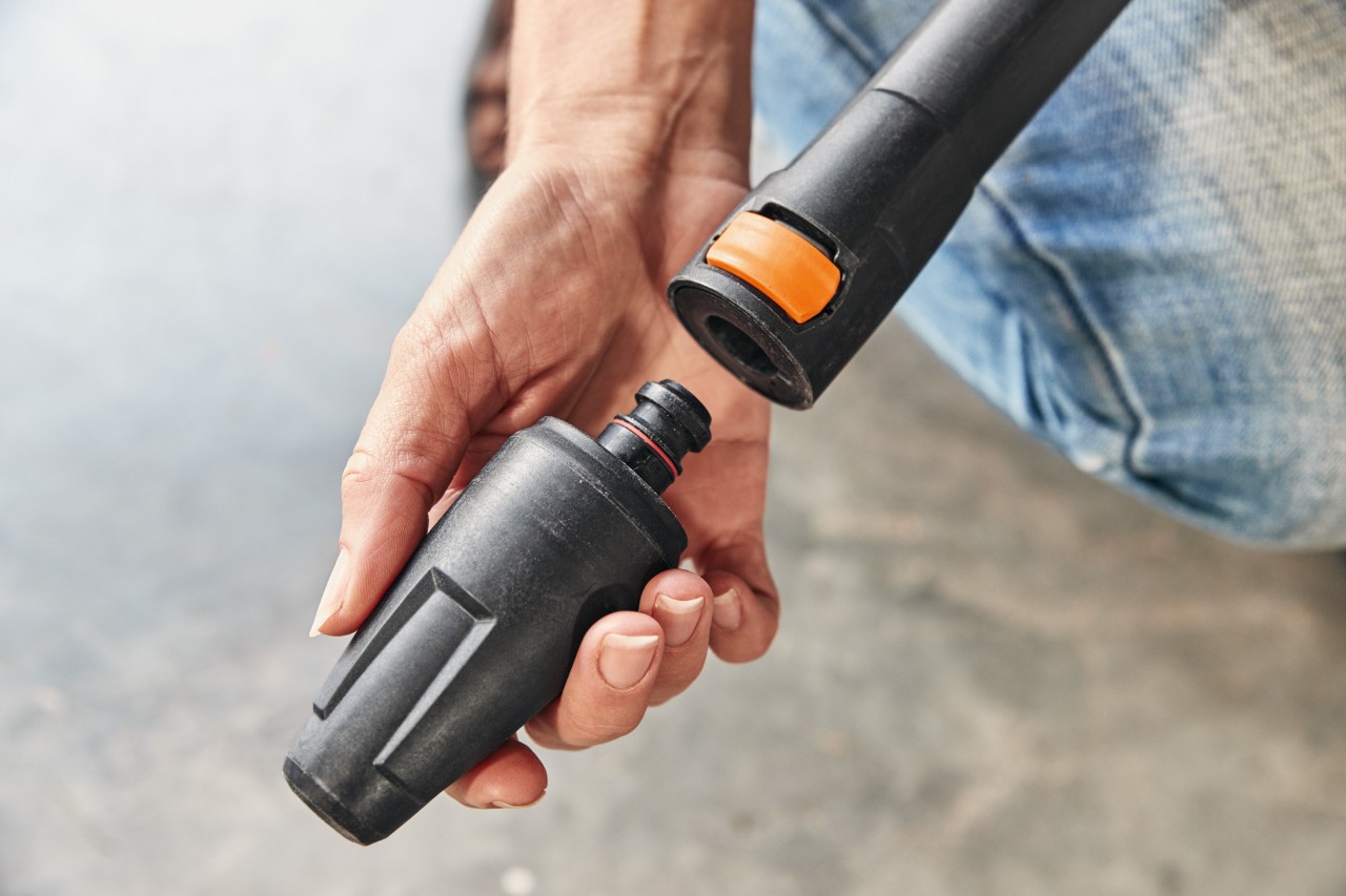  Une personne montant un embout sur le nettoyeur haute pression STIHL RE 130 PLUS en vue de son utilisation