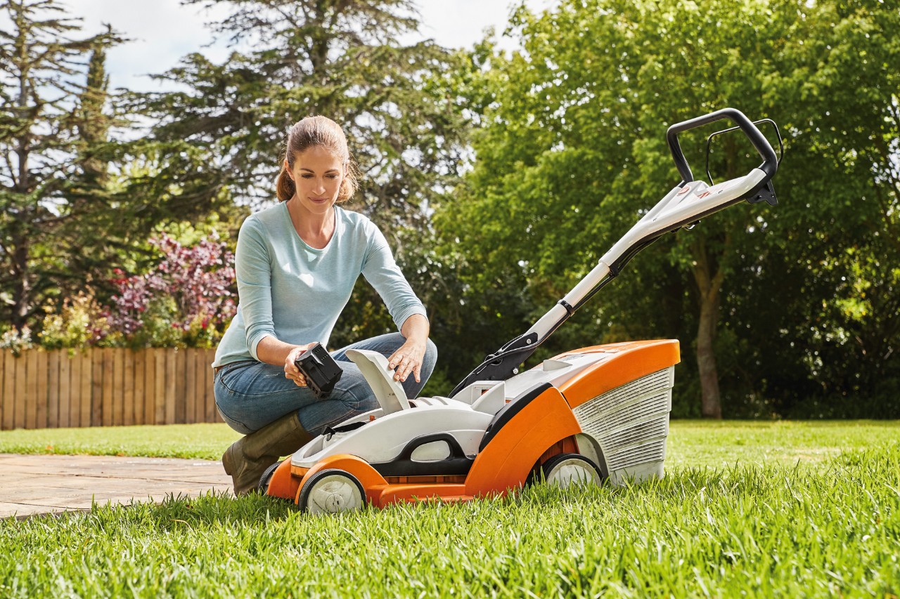 Une femme retirant la batterie d’une tondeuse à gazon STIHL RMA 339 C