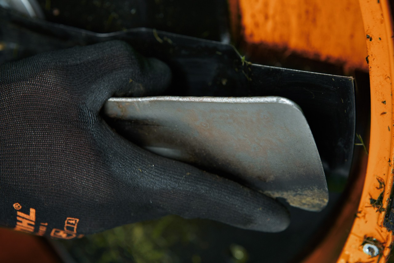 Gros plan d’une spatule utilisée pour nettoyer le dessous d’une tondeuse à gazon