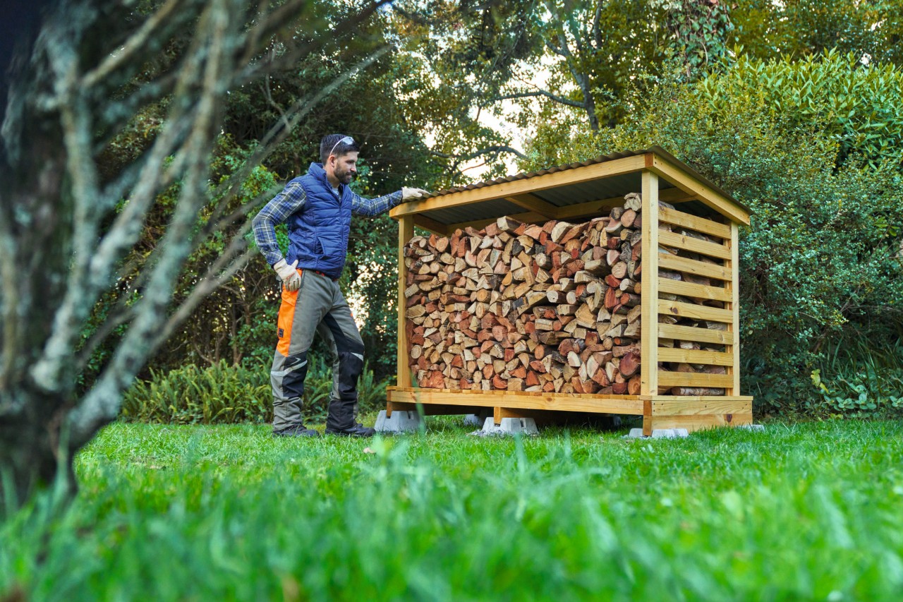 Homme en équipement de protection devant un abri à bois construit soi-même