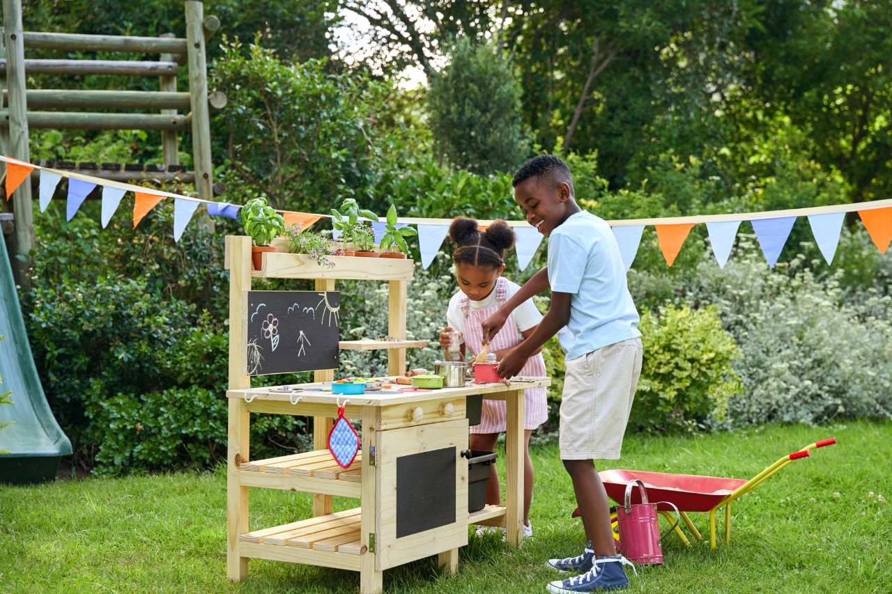 Deux enfants jouent dans le jardin dans une cuisine pour enfant.