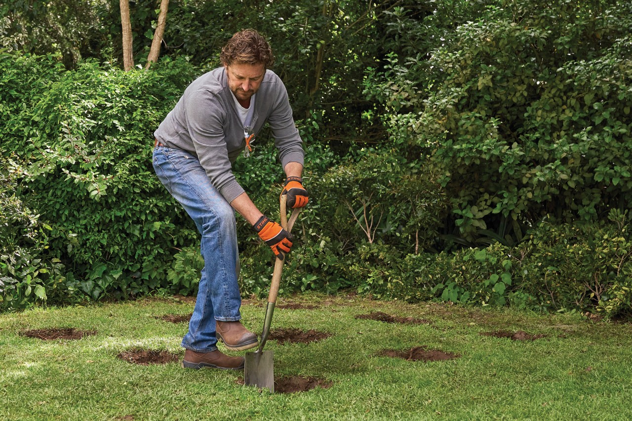 Comment construire une remise de jardin : homme utilisant une bêche pour creuser 9 trous pour les fondations sur pieux
