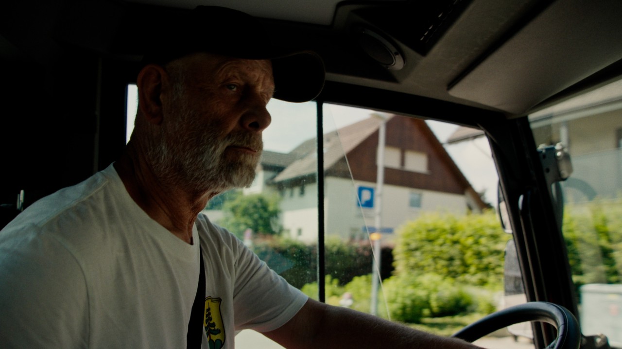 Lukas al volante di un’auto, , vista interna con volante e ambiente, campagna Real People. STIHL People.
