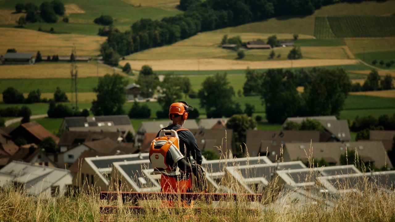 Lukas guarda il comune e porta un soffiatore STIHL BRA 600 sulla schiena, campagna Real People. STIHL People.