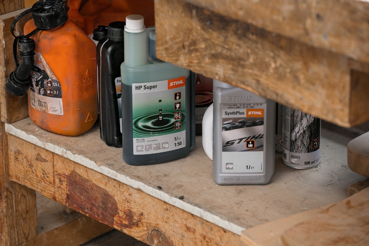 Olio per catene da motosega STIHL SynthPlus e olio per motori a reazione temporale STIHL HP Super accanto ad altri carburanti e lubrificanti in uno scaffale