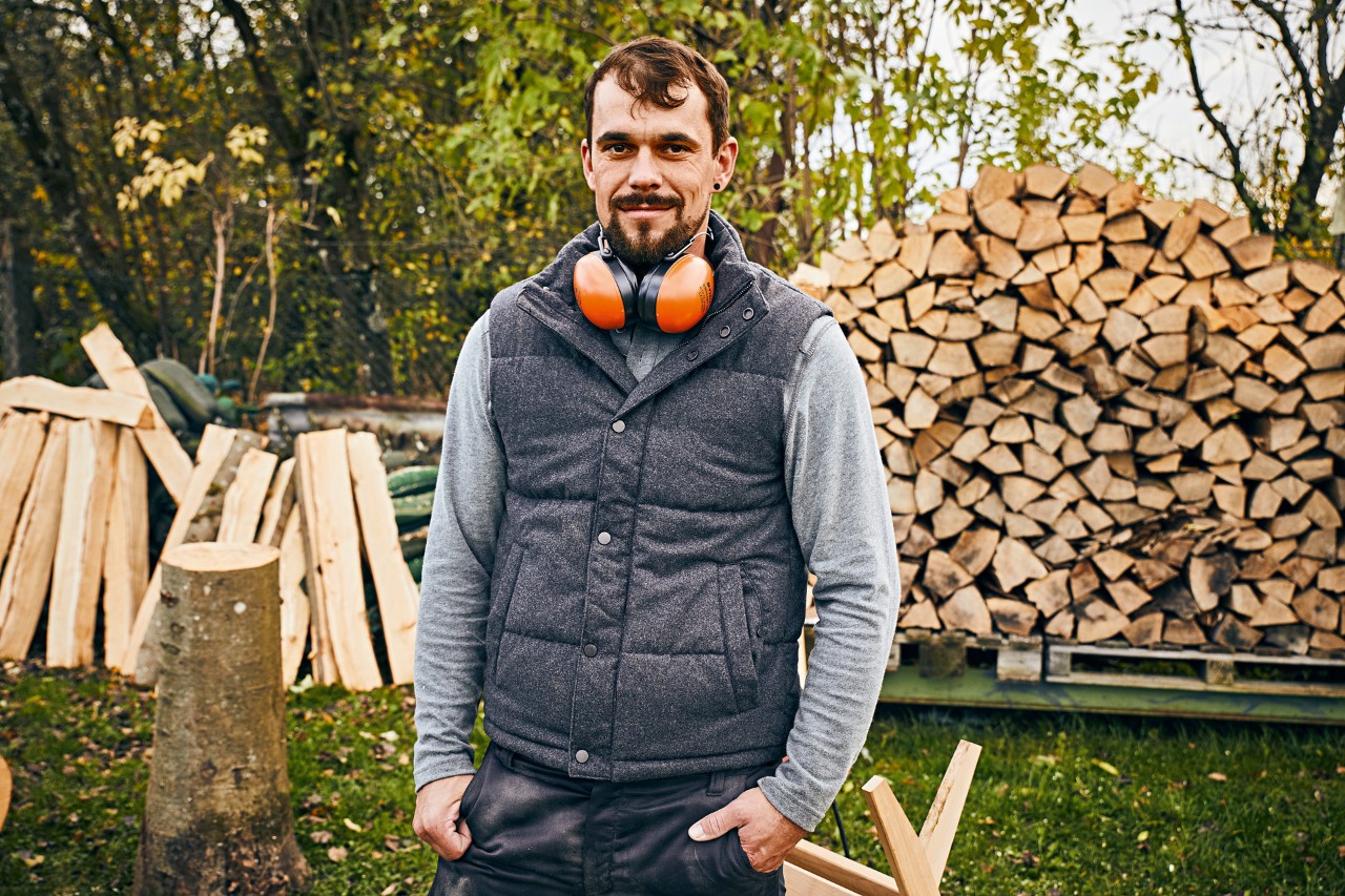 Uomo munito di cuffie protettive STIHL all'interno di un giardino davanti a una pila di ceppi