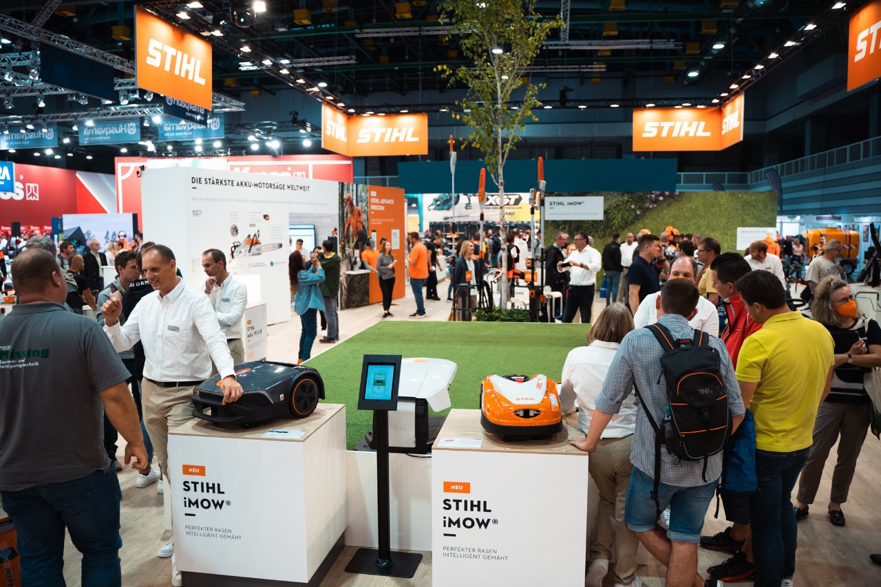 Stand fieristico interno STIHL pieno di visitatori con robot tosaerba iMOW®