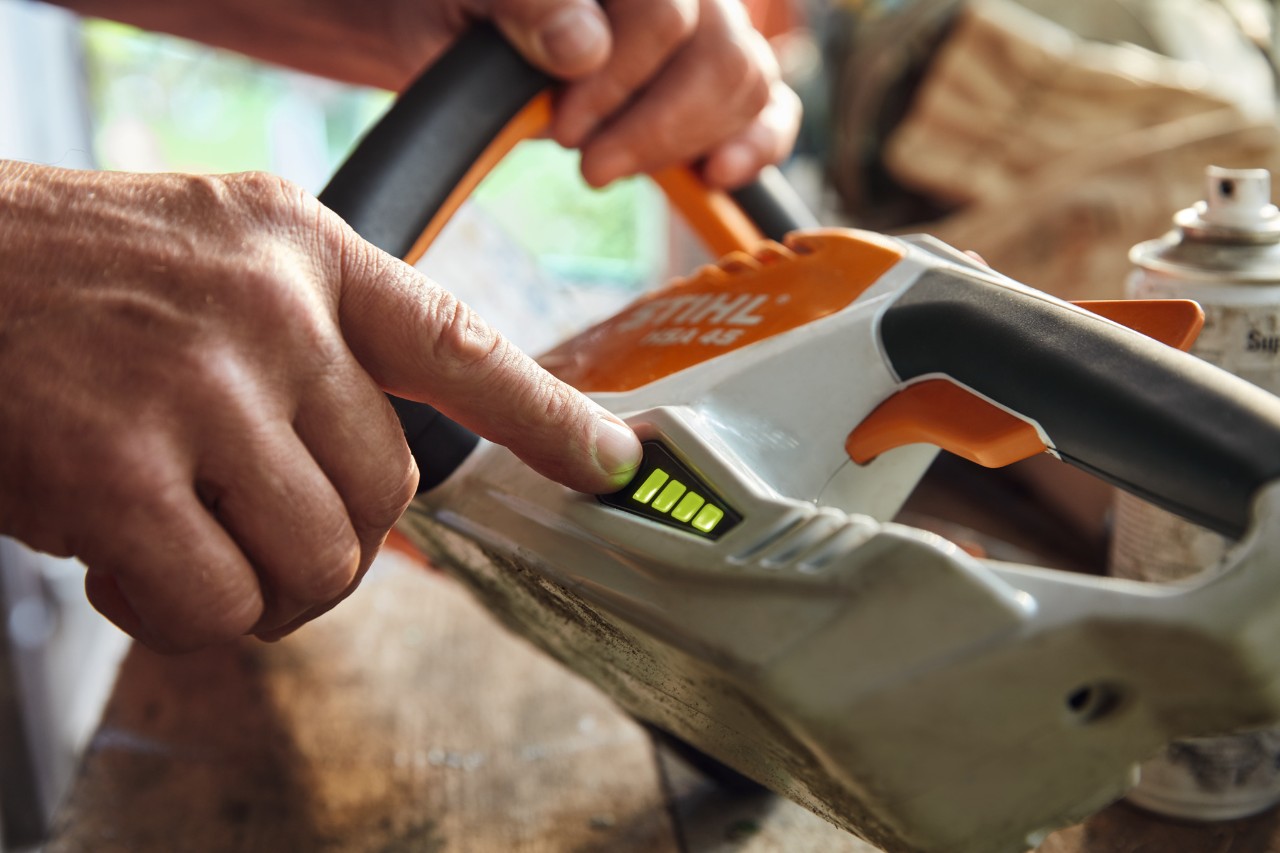 Una persona controlla il livello di carica del tagliasiepi a batteria STIHL HSA 45.