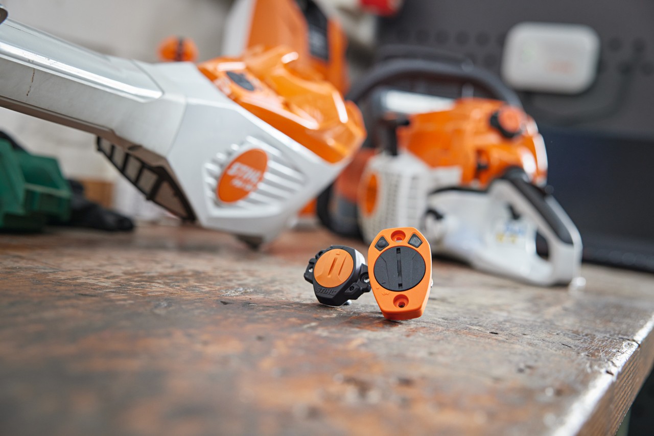 STIHL Smart Connector e STIHL Smart Connector 2 A su un banco da lavoro. Sullo sfondo si vedono varie attrezzature STIHL sfocate.