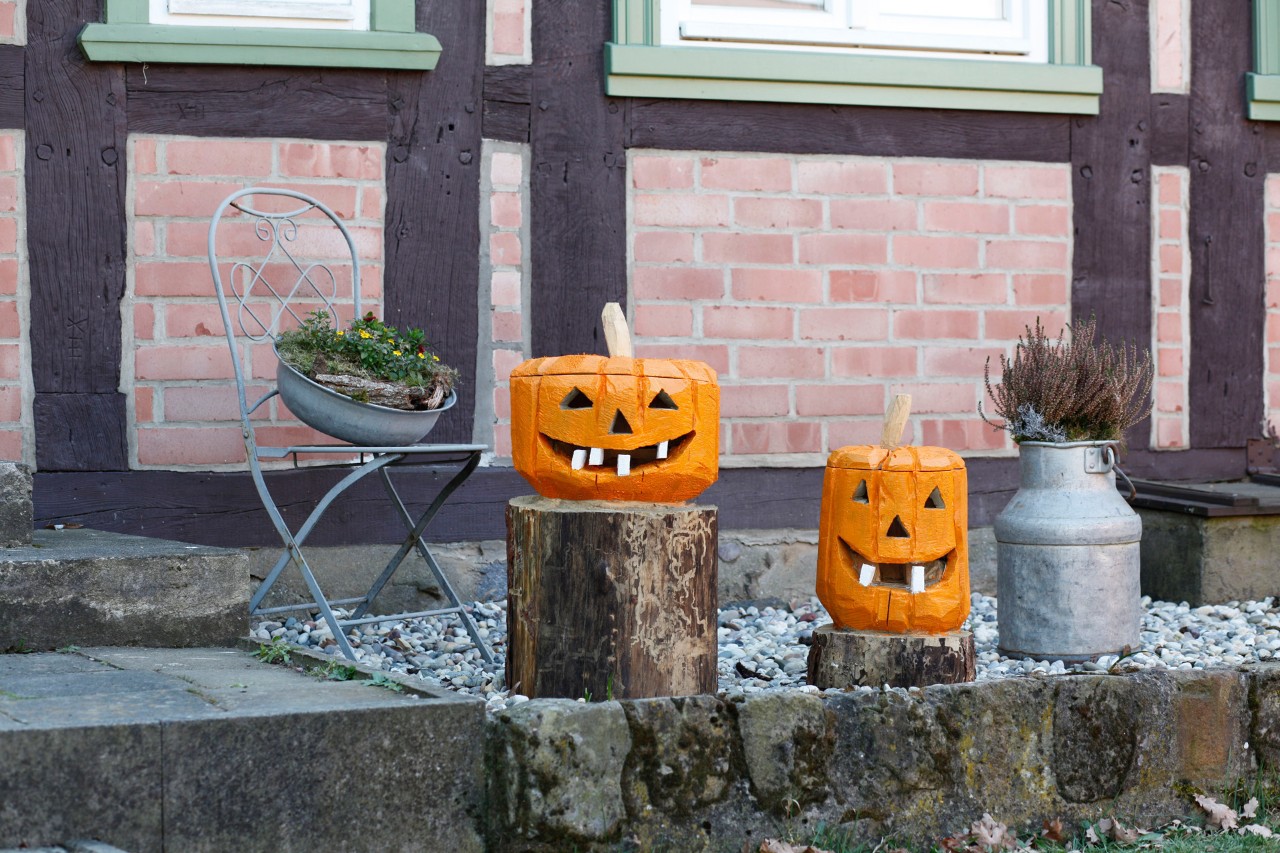Una zucca di legno fai da te su due ceppi d'albero come decorazione davanti a una casa