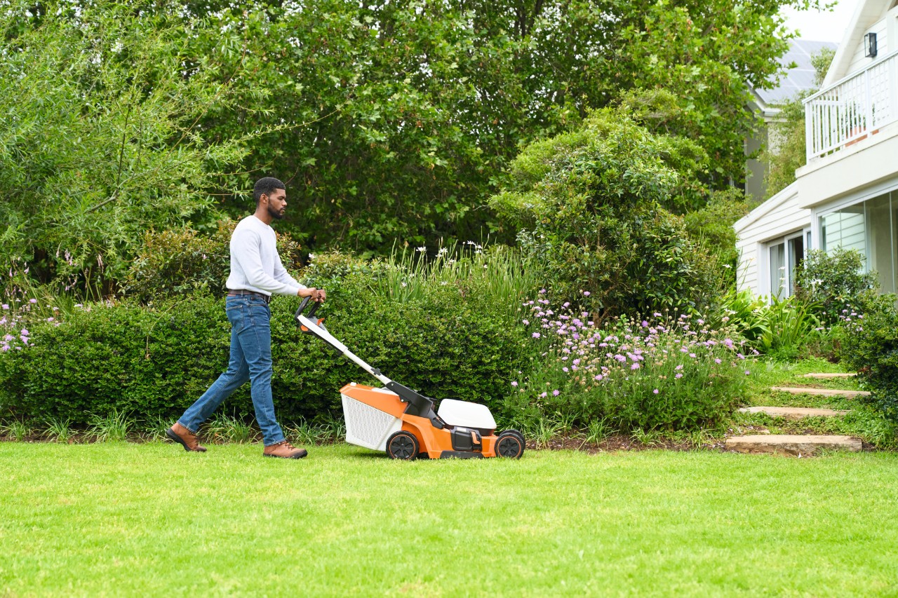 Uomo che falcia il prato con un tosaerba STIHL RMA 448 V