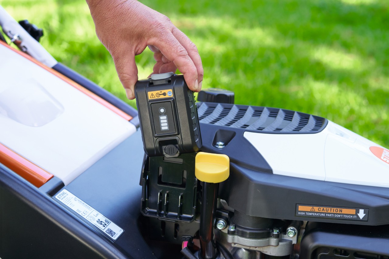 Una persona inserisce la batteria nel motore del tosaerba