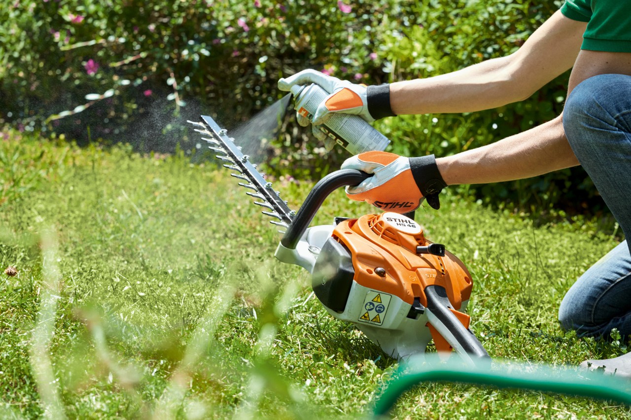  Il tagliasiepi a scoppio STIHL HS 82 T viene spruzzato sull'erba verde per pulirla