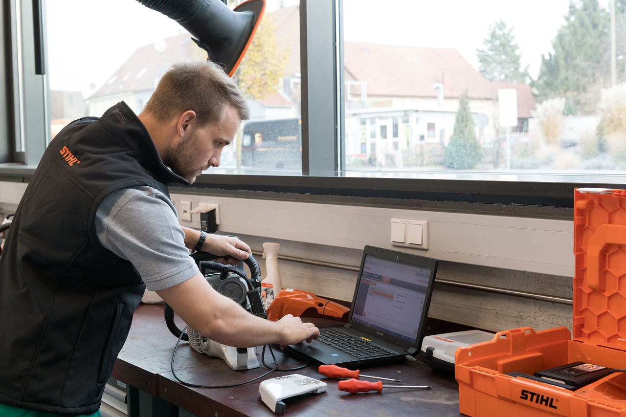 Uomo che guarda un laptop in un'officina. Accanto c'è una motosega STIHL.